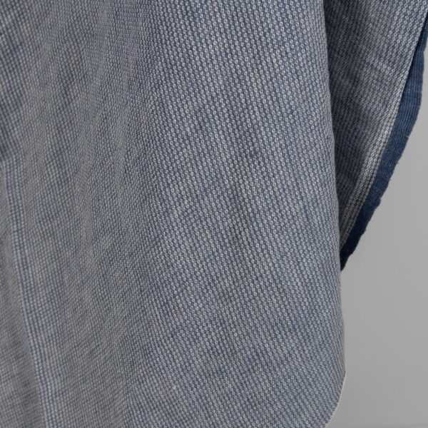 Washed linen fabric blueish grey colour small pattern close edge view
